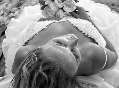Overhead shot of the bride in black and white cover looking down on her bouquet and wedding dress