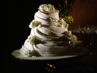 White wedding cake surrounded by special lighting to accentuate the beauty of the wedding cake 