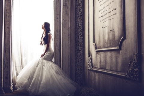 Beautiful bride in perfect wedding dress captured with window lighting at the venue where they are holding their reception